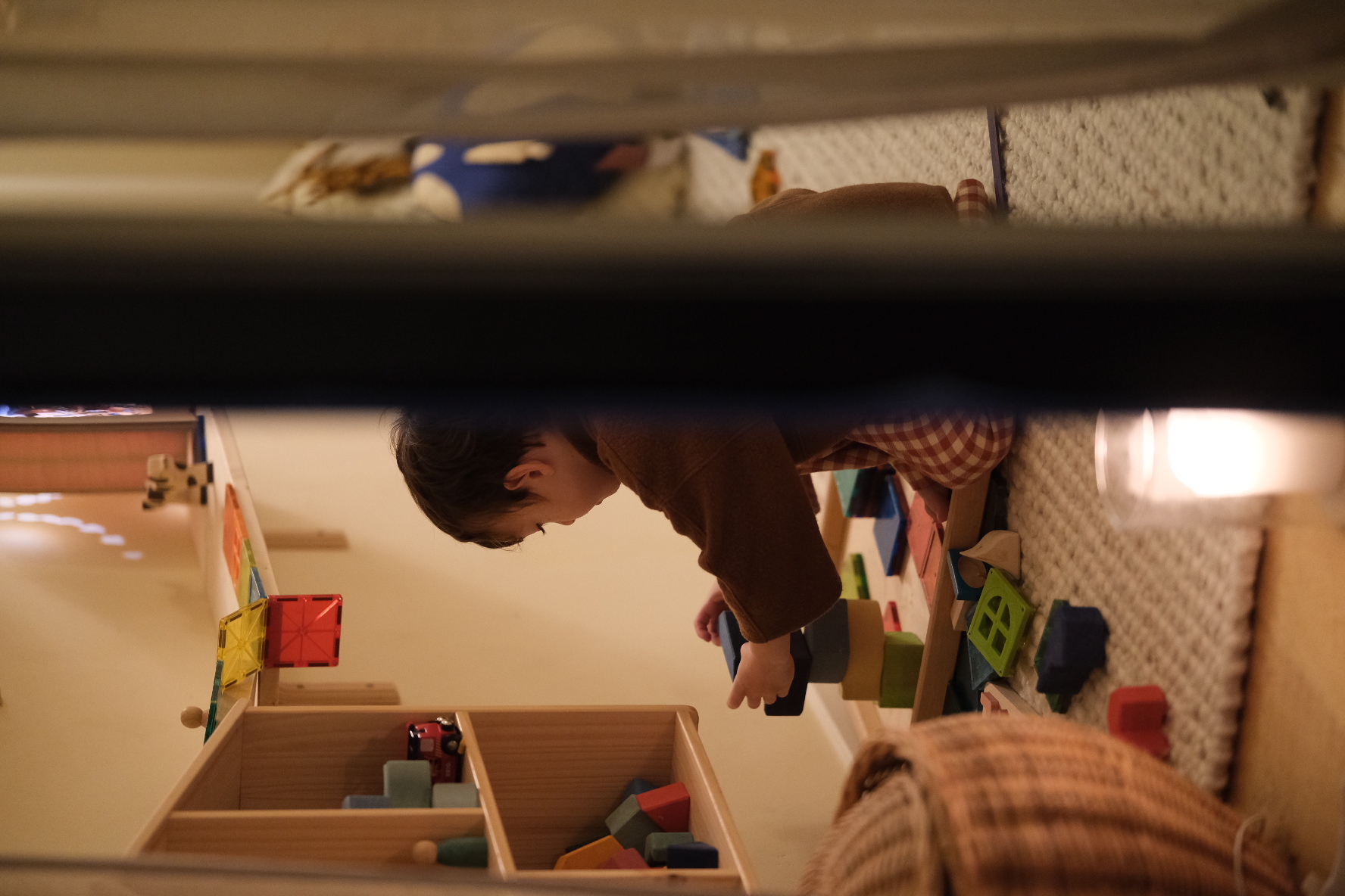 A child playing quietly with wooden blocks by candlelight